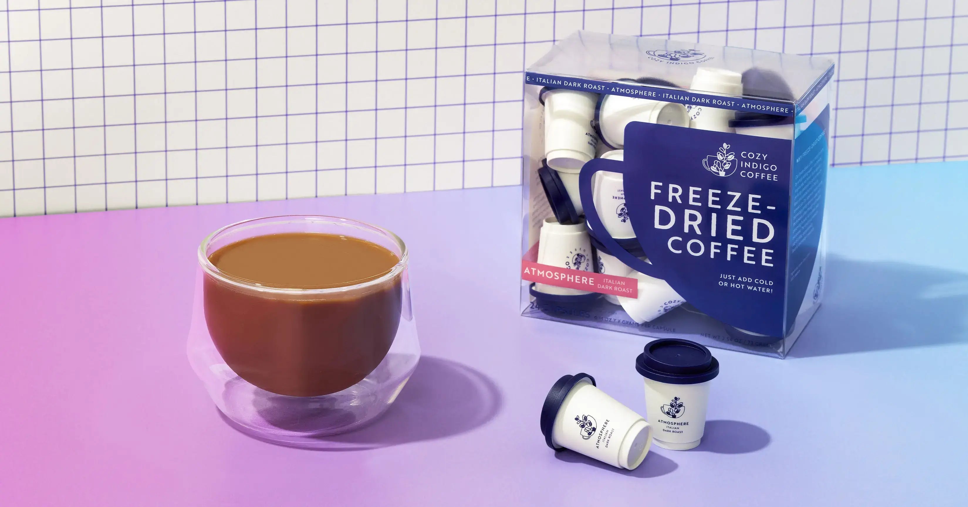 Coffee mug and freeze-dried pods on pink-purple grid | Cozy Indigo Coffee